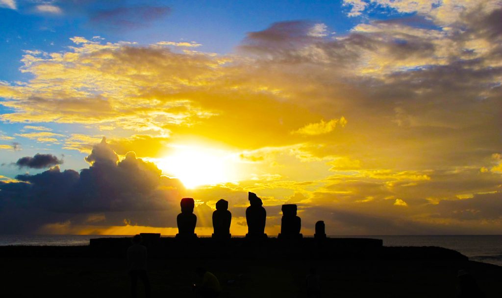 The sun sets over a group of Moai statues on Rapa Nui, commonly known as Easter Island.