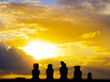 The sun sets over a group of Moai statues on Rapa Nui, commonly known as Easter Island.