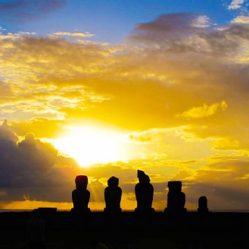 The sun sets over a group of Moai statues on Rapa Nui, commonly known as Easter Island.